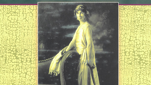 Margaret Williams stands by a couch wearing a gown and a headdress over short permed hair in what might be a photo from the 1920s.